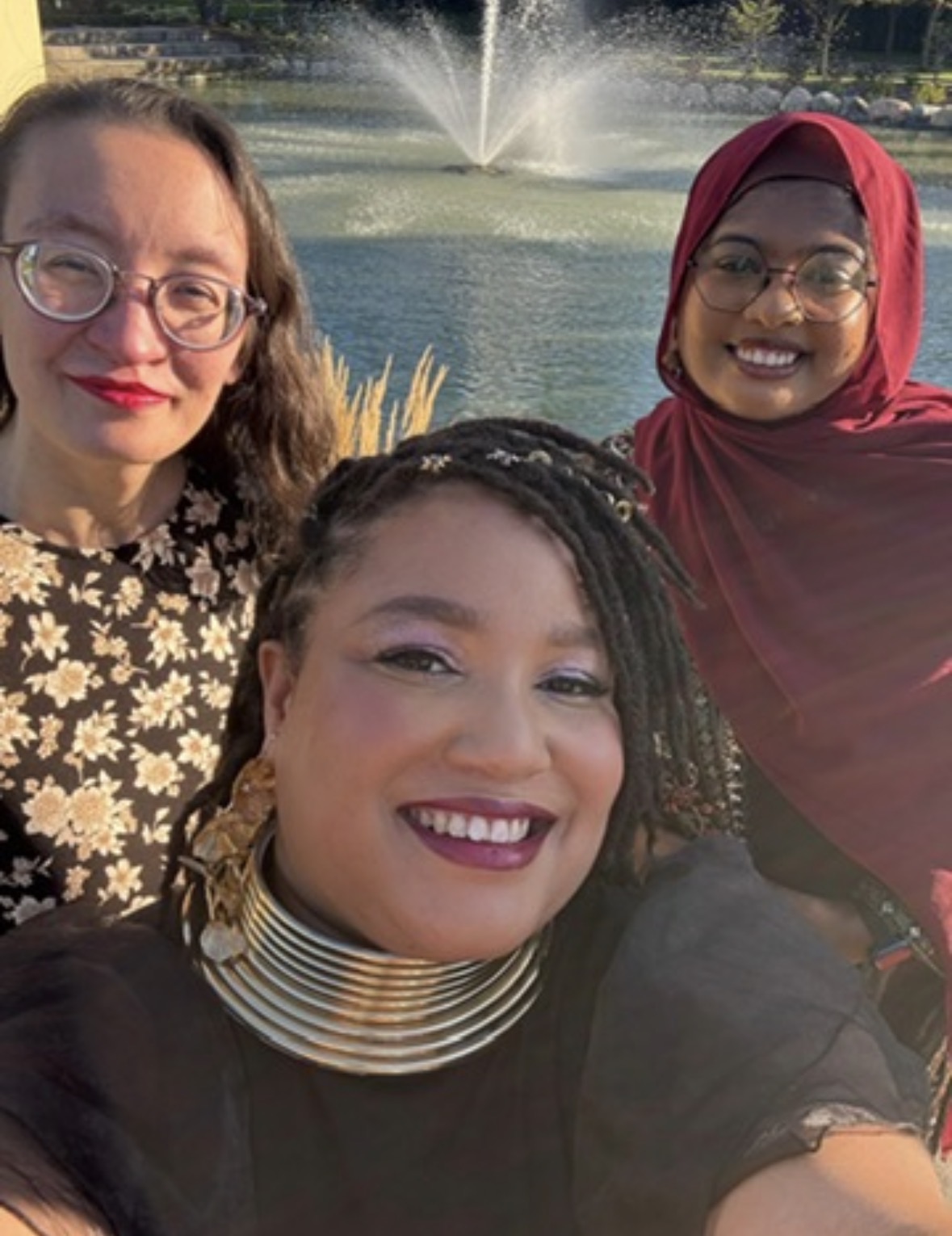Muchtar and two friends by a fountain at golden hour