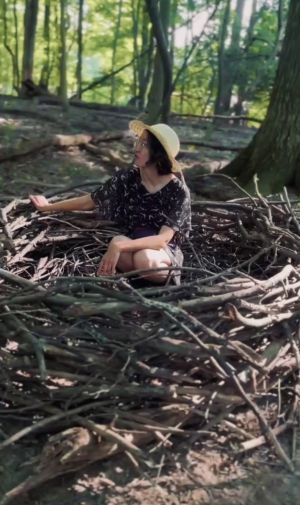 Muchtar sitting inside a giant woven nest of branches in the woods