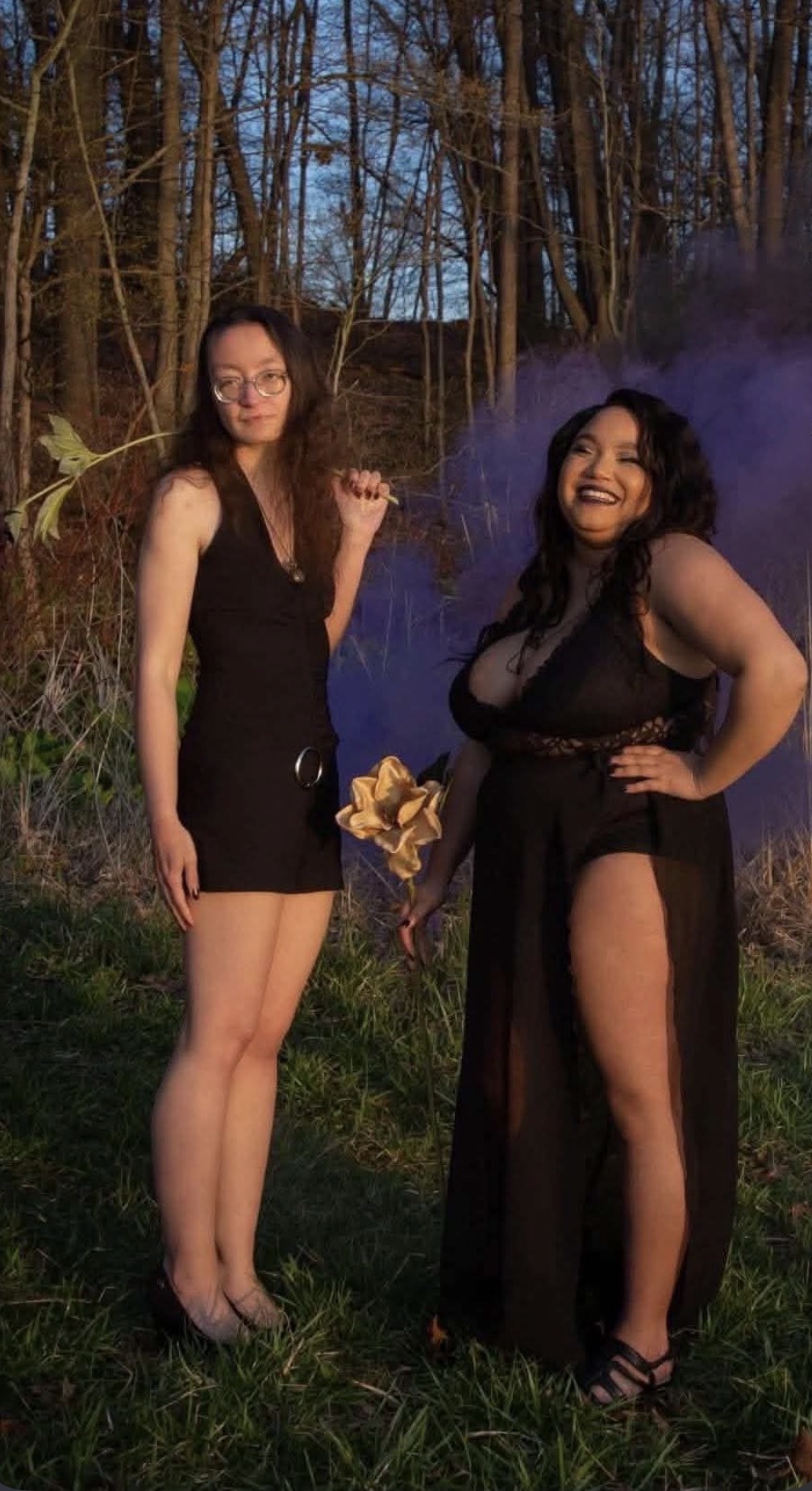 Muchtar and a friend in black dresses with purple smoke behind them